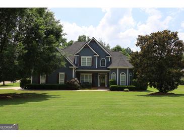 Charming two-story home features a manicured lawn and inviting facade with trees, situated on a landscaped lot at 9 Warrior Way, Sharpsburg, GA 30277