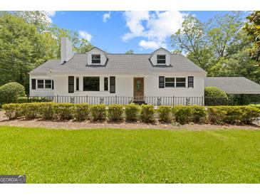 Charming home featuring a manicured lawn, black trimmed windows, and a black metal fence at 357 W Hightower Trl, Social Circle, GA 30025
