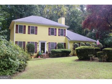 Inviting two-story yellow home featuring red shutters and well-maintained landscaping at 150 Ashley Dr, Fayetteville, GA 30214
