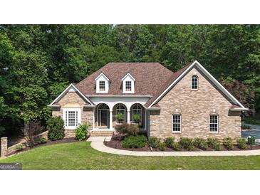 Charming brick home featuring a manicured lawn, beautiful landscaping and architectural details including dormer windows at 285 Acton Dr, Fayetteville, GA 30215