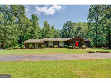 Charming ranch style home with lush greenery and mature trees surrounding the property at 2400 White Pine Ln, Mansfield, GA 30055