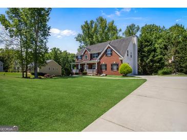 Beautiful brick home featuring a lush lawn, driveway, and lovely landscaping at 419 Tea Rose N Ln, Stockbridge, GA 30281