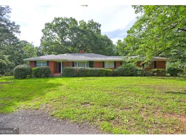 Charming brick home with lush landscaping and mature trees on an expansive green lawn at 2742 Highway 20 W, Hampton, GA 30228