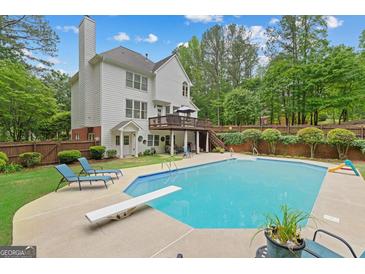 Relaxing backyard with a large pool, diving board, patio furniture, and wooded views at 495 Stonehaven Dr, Fayetteville, GA 30215