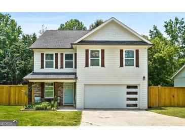 Charming two-story home with a well-manicured lawn, light blue front door, and a spacious two-car garage at 9477 Forest Knoll Dr, Jonesboro, GA 30238