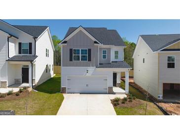 Charming two-story home with a two-car garage and manicured front lawn, perfect for suburban living at 12071 Conrad Cir, Hampton, GA 30228
