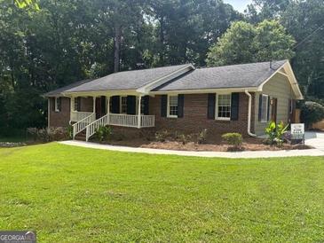 Charming brick home with a well-manicured lawn and inviting front porch perfect for relaxing at 2202 Springdale Dr, Snellville, GA 30078