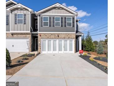 Charming two-story townhome with brick accents, white garage doors, and manicured landscaping at 11555 Kimberly Way, Hampton, GA 30228