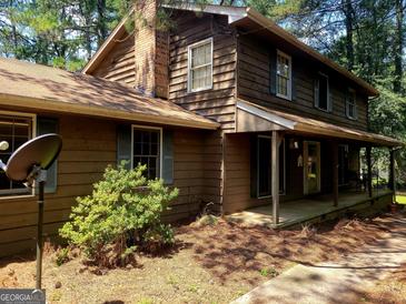 Charming two-story home with wood siding, brick chimney, and covered front porch at 963 Blackberry Ct, Ellenwood, GA 30294