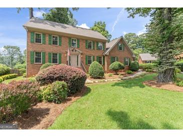 Charming brick home featuring a well-manicured lawn and vibrant green shutters at 829 Bev Ct, Lawrenceville, GA 30046