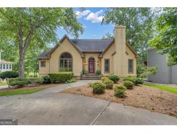 Charming stucco home featuring a red front door, mature trees, and a well-manicured lawn at 110 Tamerlane, Peachtree City, GA 30269