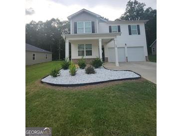 Charming two-story home featuring a welcoming front porch, manicured lawn, and a two-car garage at 160 Grafton St, Hampton, GA 30228