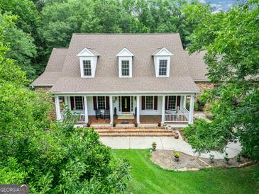 Inviting brick home featuring a covered porch,dormer windows, and a well-manicured lawn at 250 Friendship Church Rd, Brooks, GA 30205