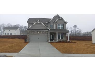 Charming two-story home with a gray facade, stone accents, and a well-manicured lawn at 6093 Ruby Fall, Stonecrest, GA 30038
