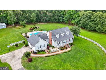 Expansive aerial view of the white home with a large backyard and a pool surrounded by black fencing at 310 Trestle Rd, Locust Grove, GA 30248