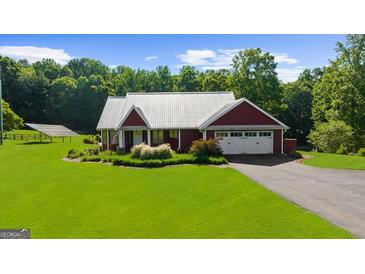 Charming single-story home features a metal roof, an attached garage, manicured lawn and solar panels for energy efficiency at 4335 Hurt Bridge Lane, Cumming, GA 30028