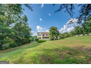 Charming two-story home with red shutters and a sprawling green lawn surrounded by mature trees at 369 Parker Rd, Mcdonough, GA 30252
