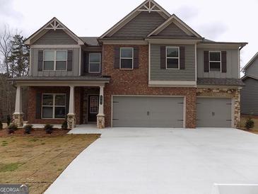 Charming two-story home featuring a brick and siding facade, a covered porch, and a spacious three-car garage at 1741 Cobblefield Cir, Dacula, GA 30019