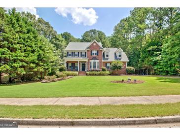 Two-story brick home with a manicured front lawn, landscaped flowerbeds, and mature trees at 145 Driftwood Trl, Fayetteville, GA 30215