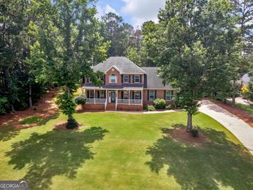 Stately brick home with a lush green lawn and mature trees offering curb appeal and a welcoming entrance at 416 River Forest Dr, Mcdonough, GA 30252
