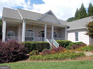 Charming brick home featuring a welcoming front porch and beautifully landscaped front yard with colorful flowers at 216 Lake Tanisha Dr, Dallas, GA 30157