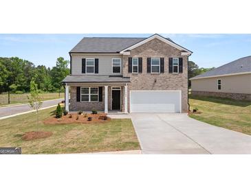 Charming two-story home featuring brick and gray siding, black shutters, manicured lawn, and an attached two-car garage at 612 Whitman Ln, Stockbridge, GA 30281