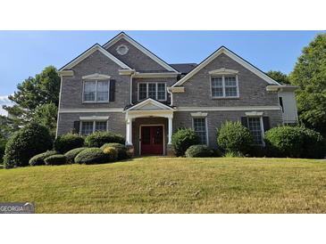 Charming brick home featuring a manicured lawn, symmetrical design, and a welcoming double-door entrance at 7235 Thoreau Cir, Atlanta, GA 30349