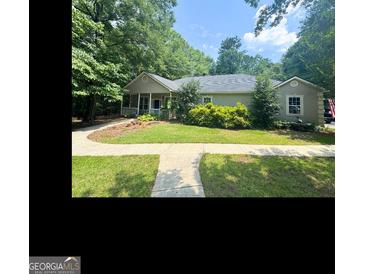 Charming single-story home with a covered front porch and lush landscaping surrounding the property at 180 Tabor Forest Dr, Oxford, GA 30054