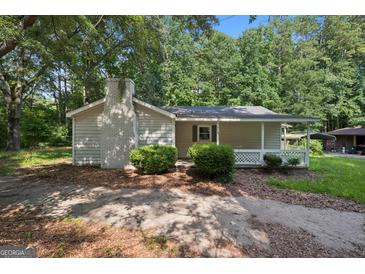 Charming single-story home with a brick chimney, a quaint front porch, and mature landscaping at 6770 Burkhead Dr, Union City, GA 30291