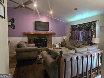 Cozy living room features a stone fireplace, plush seating, and a ceiling fan at 2071 Scarbrough, Stone Mountain, GA 30088