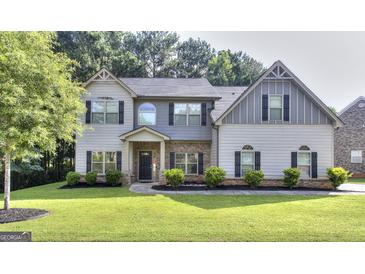 Charming two-story home with well-manicured lawn, complemented by lush landscaping and mature trees at 2817 Village Park E Dr, Ellenwood, GA 30294