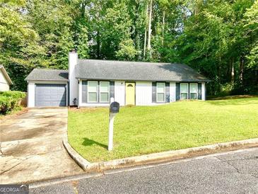 Charming ranch-style home featuring a well-manicured lawn, gray shutters, and a yellow front door at 3248 Brisbane Way, Lithonia, GA 30038