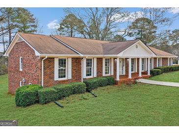 Charming brick home featuring a welcoming front porch with classic white columns at 210 Heritage Cir, Mcdonough, GA 30253