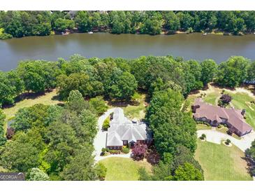 Aerial view of a brick home surrounded by mature trees, with river access and a well-manicured lawn at 660 Milton Dr, Mcdonough, GA 30252
