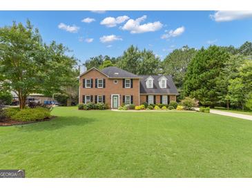 Traditional two-story brick home with a well-manicured lawn and mature trees at 127 Rockspray Rdg, Peachtree City, GA 30269