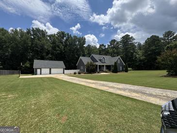 Beautiful two-story home features a long drive, lush lawn, and a detached two-car garage at 180 Cooper Rd, Social Circle, GA 30025