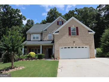 Inviting brick two-story home featuring a well-manicured lawn, two-car garage and charming front porch at 305 Matthew Cir, Stockbridge, GA 30252