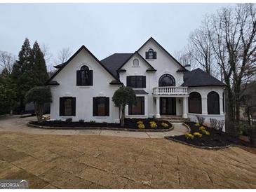 Stunning two-story home with a white stucco exterior, black shutters, a circular balcony, and professionally landscaped yard at 7910 Tintern Trce, Duluth, GA 30097