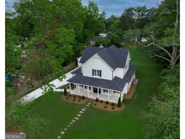 Inviting two-story home with a charming front porch, lush lawn, and a long driveway at 61 Main St, Moreland, GA 30259