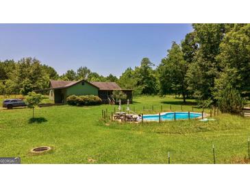 Charming home with a pool, surrounded by lush greenery and a spacious yard, perfect for outdoor living at 1828 Pitts Chapel Rd, Newborn, GA 30056