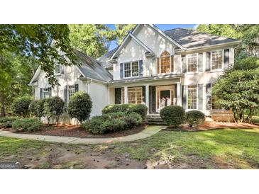 Elegant two-story home featuring a stucco facade, black shutters, and manicured landscaping at 1202 Loxley Cir, Peachtree City, GA 30269
