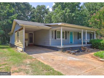 Charming single-story home with a covered front porch, carport, and a bright blue front door at 315 Charlotte Blvd, Stockbridge, GA 30281