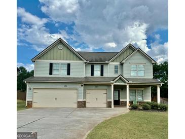 Charming two-story home featuring a three-car garage, well-maintained lawn, and welcoming front porch at 9108 Alden Dr, Locust Grove, GA 30248