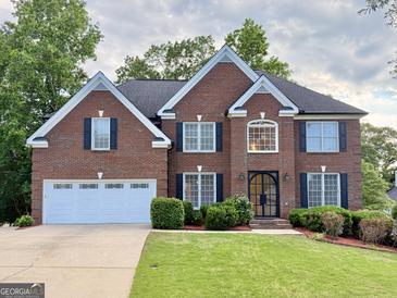 Stately brick home with a manicured lawn and a two-car garage at 6765 Crofton Dr, Alpharetta, GA 30005