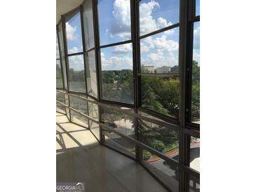 Spacious balcony with floor to ceiling windows offering a stunning view of the city and lush greenery at 3060 Nw Pharr Ct # 517, Atlanta, GA 30305