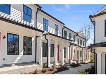 View of modern townhome exteriors with white siding, black trim, and covered entryways; blue skies above at 88 Black Gum Ln # 43, Auburn, GA 30011
