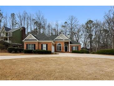 Charming single-story home with a well-manicured lawn, brick facade, and mature trees at 5055 Hickory Hills Dr, Woodstock, GA 30188