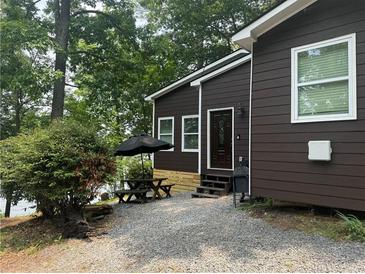 Charming exterior view of the lake house, featuring a front patio with a table, chairs, and a well-maintained yard at 7 Yachting Way, Acworth, GA 30102