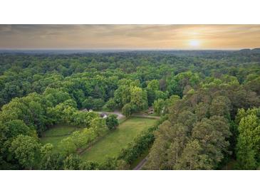 A sprawling wooded property featuring lush greenery and a home nestled among mature trees at 2585 Gelding Ne Ct, Marietta, GA 30062