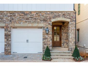 Elegant stone facade with arched doorway and white garage door creates a welcoming entrance at 220 Alcovy Ter, Alpharetta, GA 30009